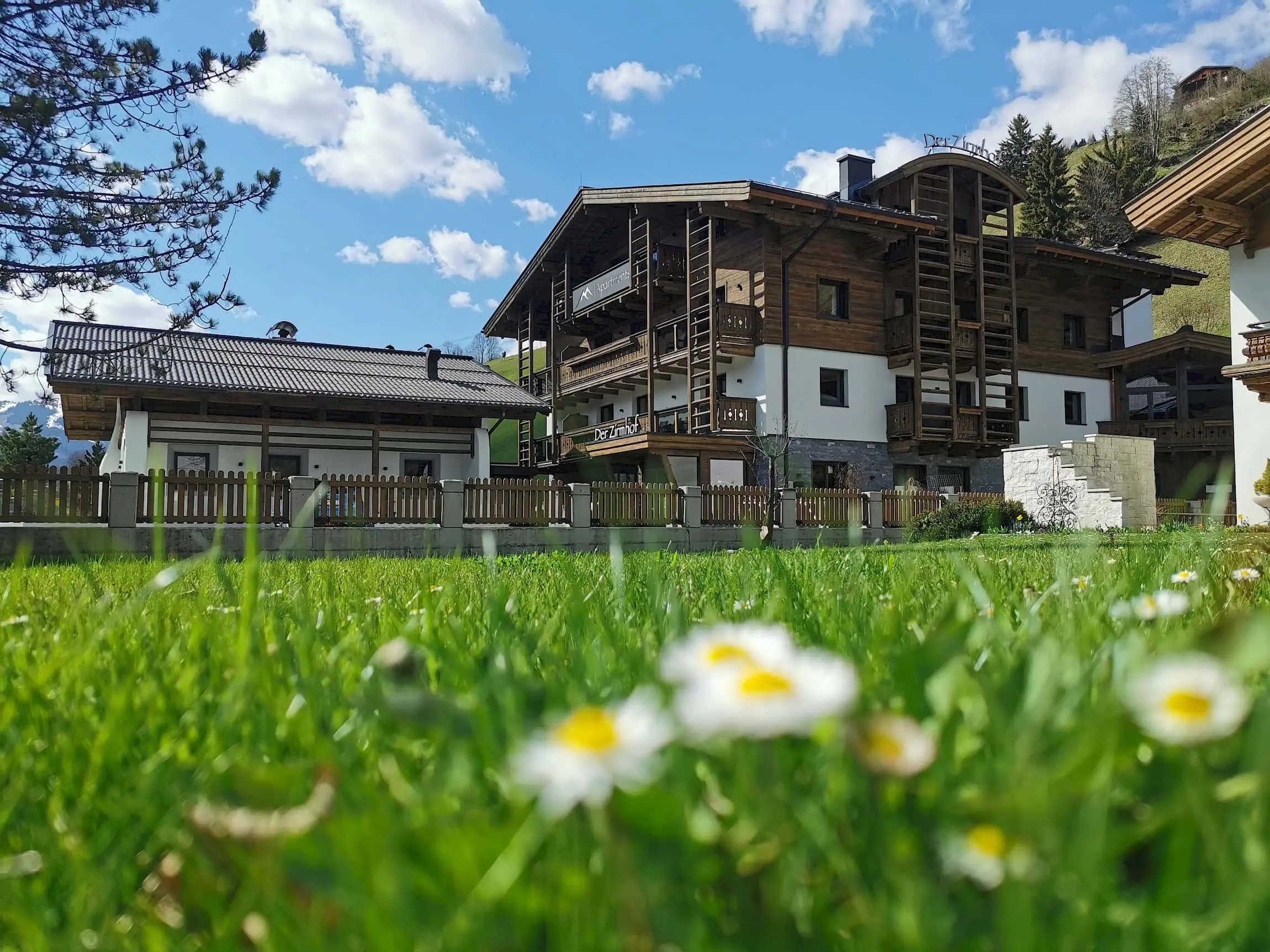 Exterior view of the Zirmhof Apartments in winter. In the background the Schönleitenbahn and the piste.