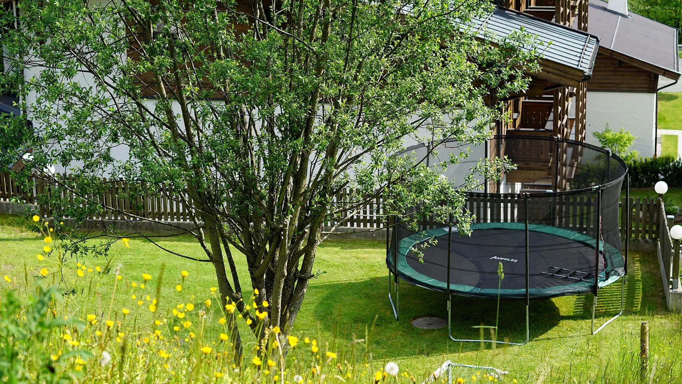 Spielplatz mit Trampolin, rundherum Wiese | Zirmhof Apartments