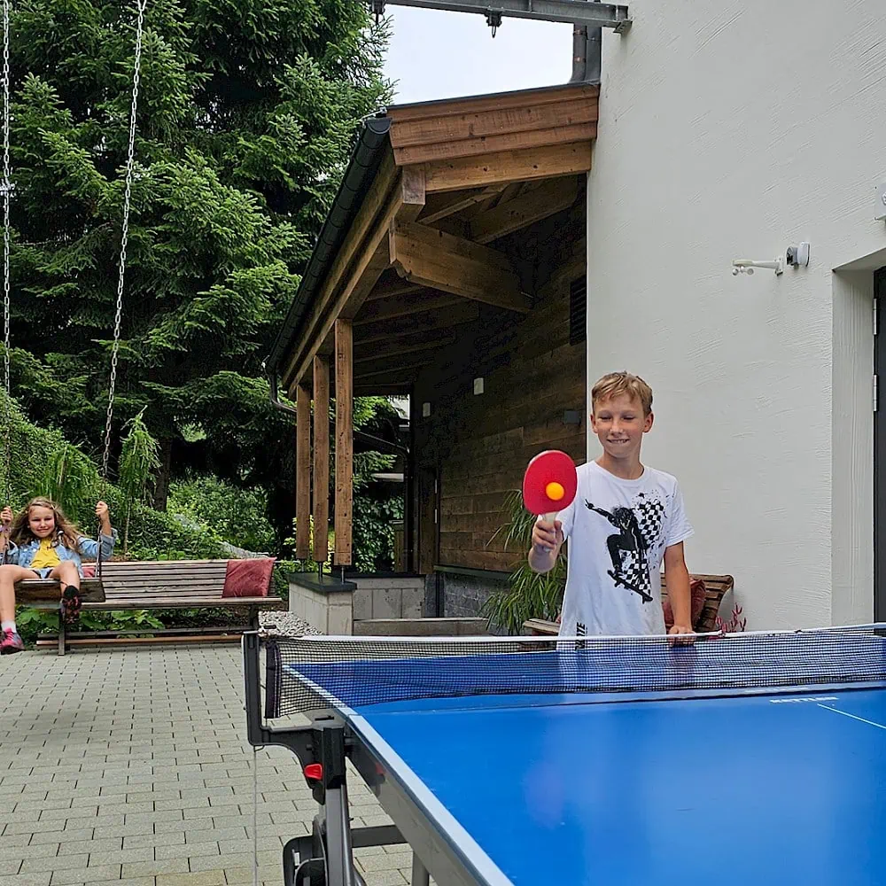 Boy plays table tennis and girl swings behind the Zirmhof